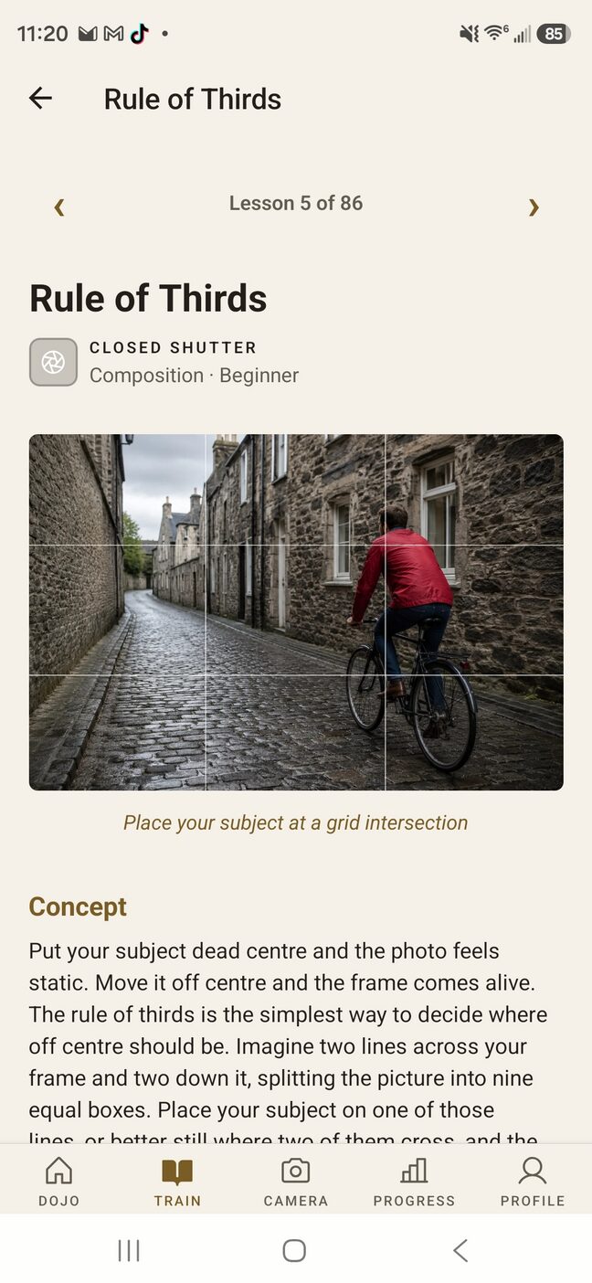 The Rule of Thirds lesson, lesson five of eighty-six in Closed Shutter. The lesson illustration shows a cobbled street with a cyclist in a red jacket sitting on the right vertical line, thirds grid overlaid, captioned “Place your subject at a grid intersection.”